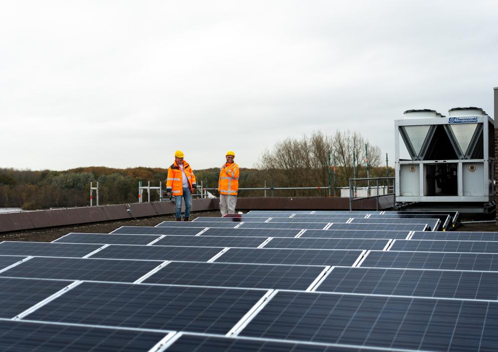 2 medewerkers lopen op een dak vol zonnepanelen