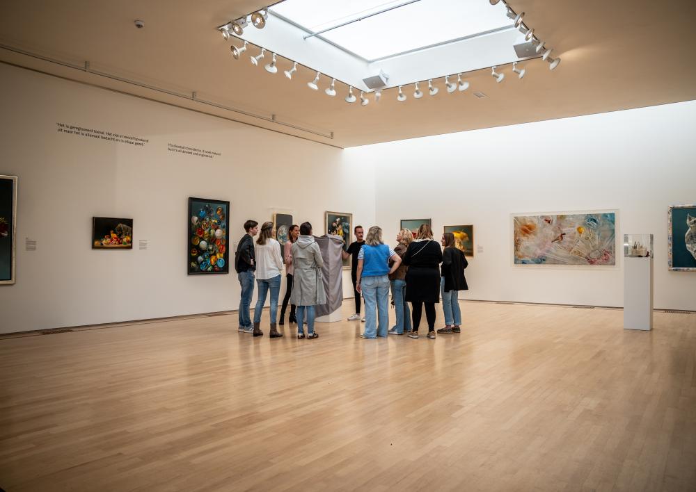 Een groep mensen staat om een kunstwerk in een museumzaal