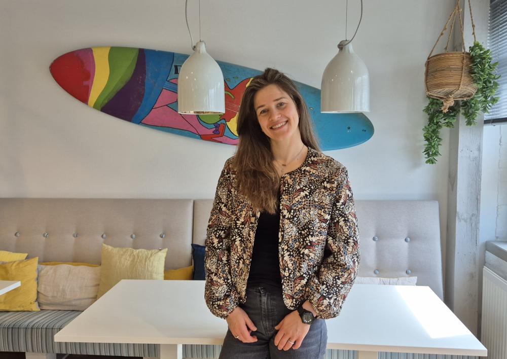 Carmen in de koffietuin met surfboard op de muur als achtergrond