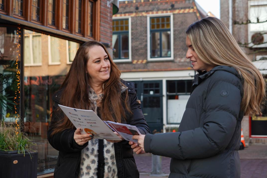 Stefanie deelt als adviseur OOV een brochure uit aan een voorbijgangster in het Oude Dorp