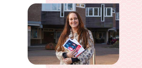 Stefanie staat voor het raadhuis met een brochure over cyberveiligheid in haar hand