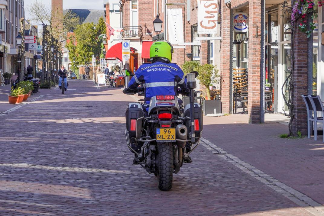 Achteraanzicht: BOA Chokri rijdt weg op de motor in het Oude Dorp
