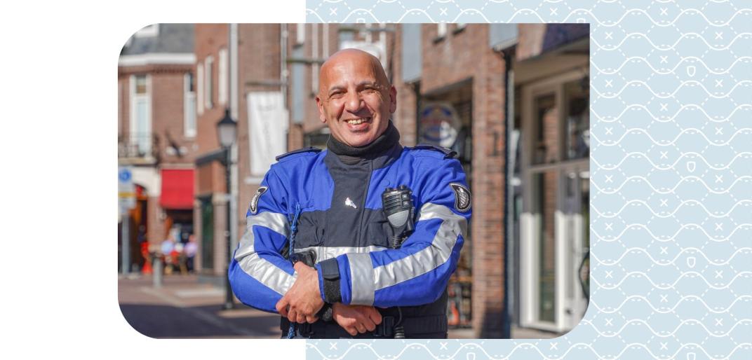 Chokri lachend met armen over elkaar in handhavers uniform