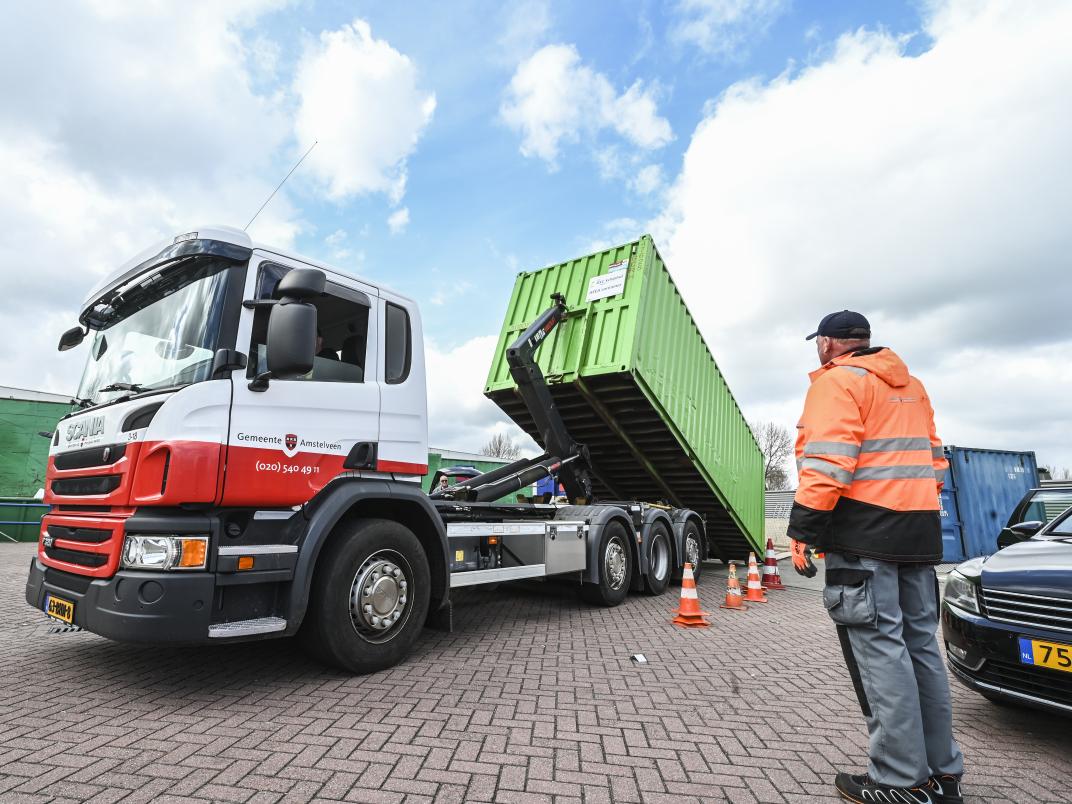 Medewerker van het afvalbrengstation bij een afvalwagen