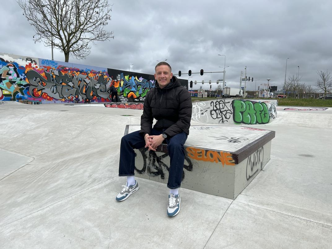 Mitchel bij de skatebaan, zittend op een betonnen blok