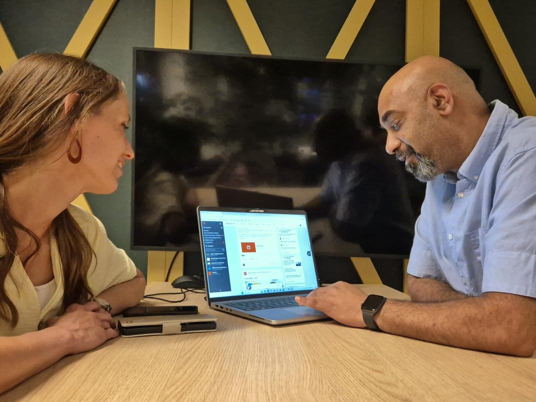 Rayner bij de servicedesk met een collega kijkend naar een laptop