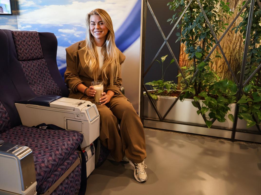 Veerle op een vliegtuigstoel in de koffieruimte