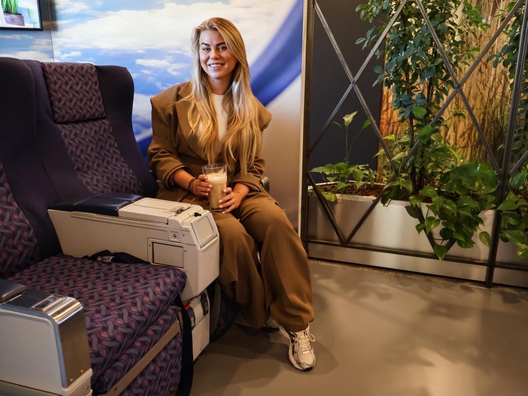 Veerle op een vliegtuigstoel in de koffieruimte