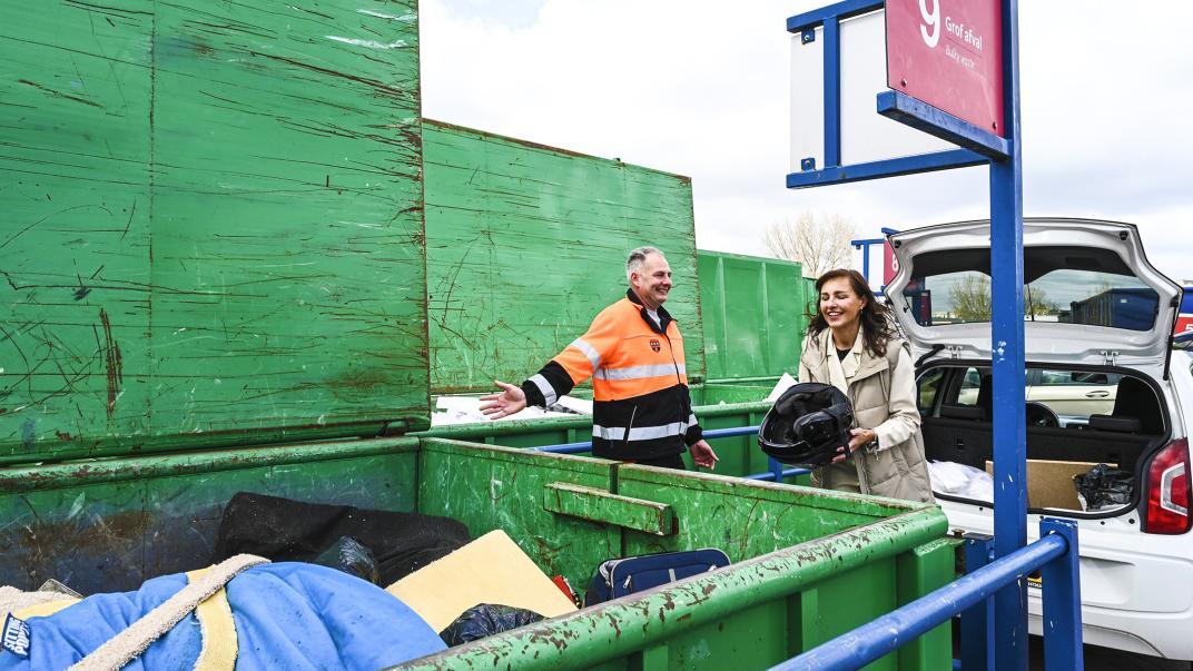 Medewerker van het afvalbrengstation bij een afvalwagen
