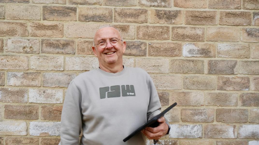 Ron met een tablet voor een muur