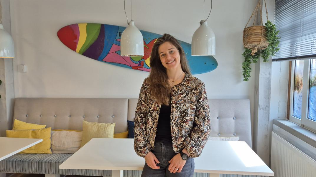 Carmen in de koffietuin met surfboard op de muur als achtergrond