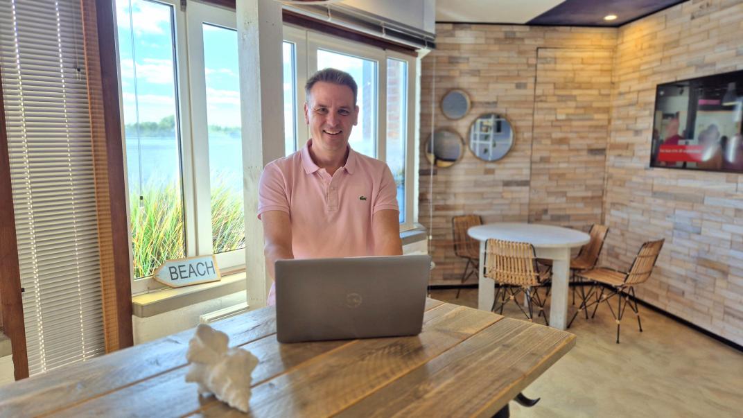 Onno in koffietuin in strand-thema met laptop op tafel